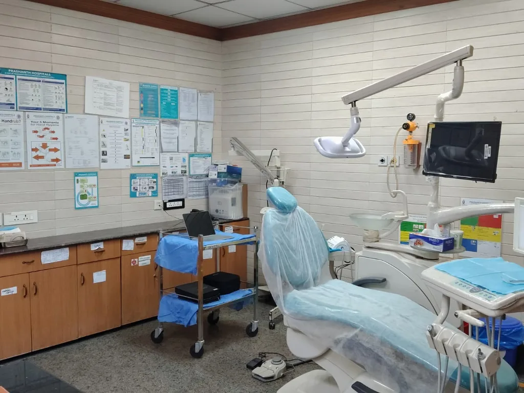 The dental treatment room: a patient chair under its overhead light, with the monitor, instrument tray and a trolley beside it
