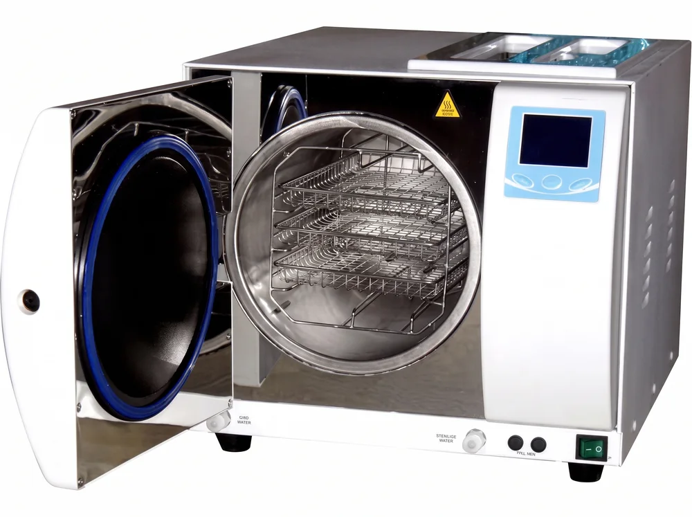 Steam autoclave with its door open, showing the instrument trays inside